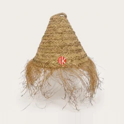 Studio shot of a chevron woven palm leaf conical lampshade with a long fringe against a white background.
