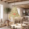 A handwoven palm leaf lampshade hanging over a wooden dining table in a sunlit coastal villa.