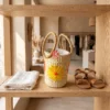 Floral Embroidered Seagrass Round Handbag with Circular Handles 2 A floral embroidered seagrass handbag sits on a light-colored wooden table in a sunlit Mediterranean boutique.