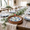 A pair of round trays with blue floral mother of pearl mosaic centers resting on a white table next to a flower.