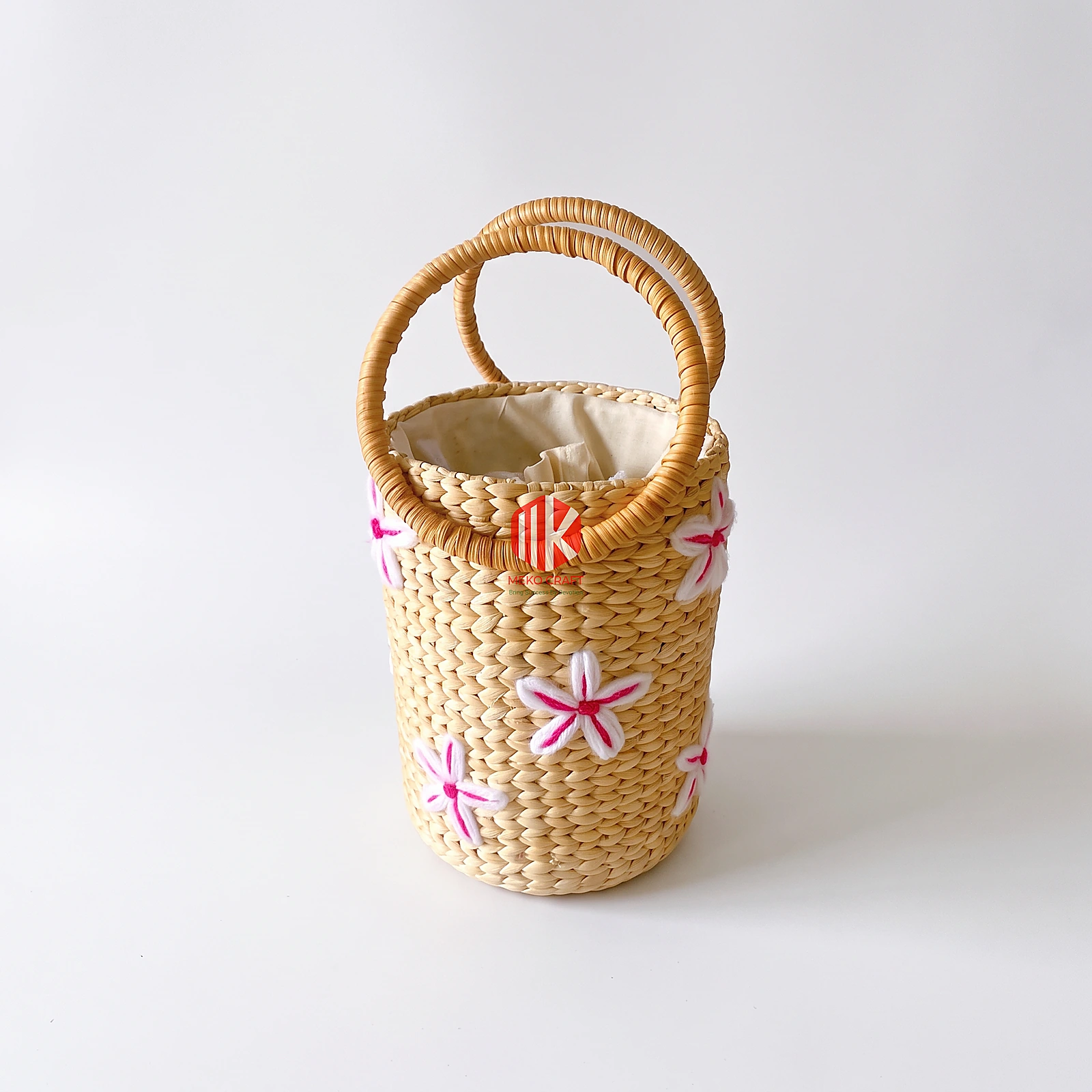 Handwoven Water Hyacinth Handbag with Floral Embroidery 2 Studio shot of a cylindrical water hyacinth handbag with white and pink floral embroidery and two round top handles on a white background.