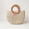 Sunburst Woven Seagrass Half Moon Handbag with Rattan Handles 1 Studio shot of a semi-circular seagrass bag with round rattan handles on a white background showing the sunburst weave pattern.