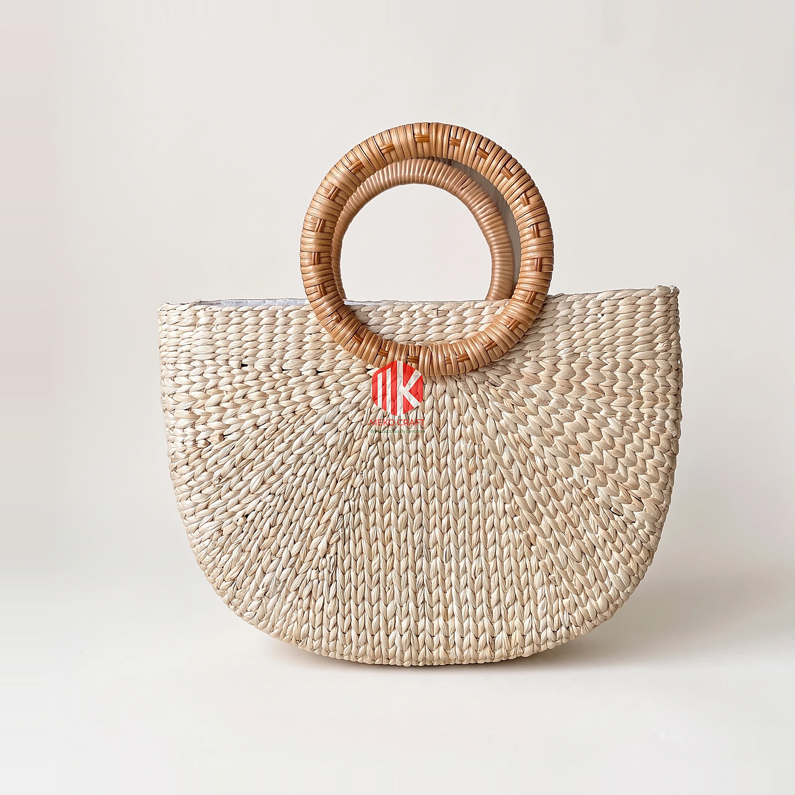 Sunburst Woven Seagrass Half Moon Handbag with Rattan Handles 3 Studio shot of a semi-circular seagrass bag with round rattan handles on a white background showing the sunburst weave pattern.