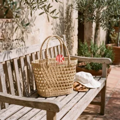 Meko Craft - Vietnam Handicraft Factory 13 A water hyacinth handbag with an open lattice weave rests on a sunlit wooden bench at a coastal resort.