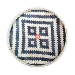 Top-down studio shot of a round handwoven bamboo tray with a black and natural geometric pattern on a white background.