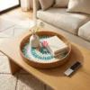Patterned Rattan and Mother of Pearl Round Serving Tray 1 A patterned rattan and mother of pearl round serving tray rests on a light-colored console table, holding a small vase and a book.
