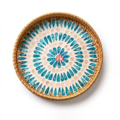 A round tray features a handwoven rattan rim and an intricate inlaid pattern of iridescent mother of pearl and blue shell pieces.