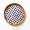 Checkerboard Rattan and Mother of Pearl Round Serving Tray 1 Overhead studio shot of a round serving tray with a woven rattan rim and a checkerboard pattern of white mother of pearl and blue squares on a white background.