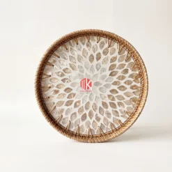 Top-down studio shot of a round tray showing the white and tan mother of pearl petal mosaic and the woven rattan rim.