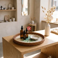 Handcrafted round mother of pearl tray with green mosaic center displayed on a boutique retail wooden table with perfume bottles.