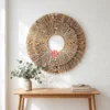 Triple Layer Palm Leaf Sunburst Wall Mirror Frame 1 A round palm leaf sunburst mirror hanging on a light grey living room wall above a modern oak sideboard.