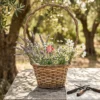 Handwoven Rattan Round Flower Planter with Arched Handle 1 A round rattan flower planter with an arched handle filled with white roses on a rustic wooden wedding table.